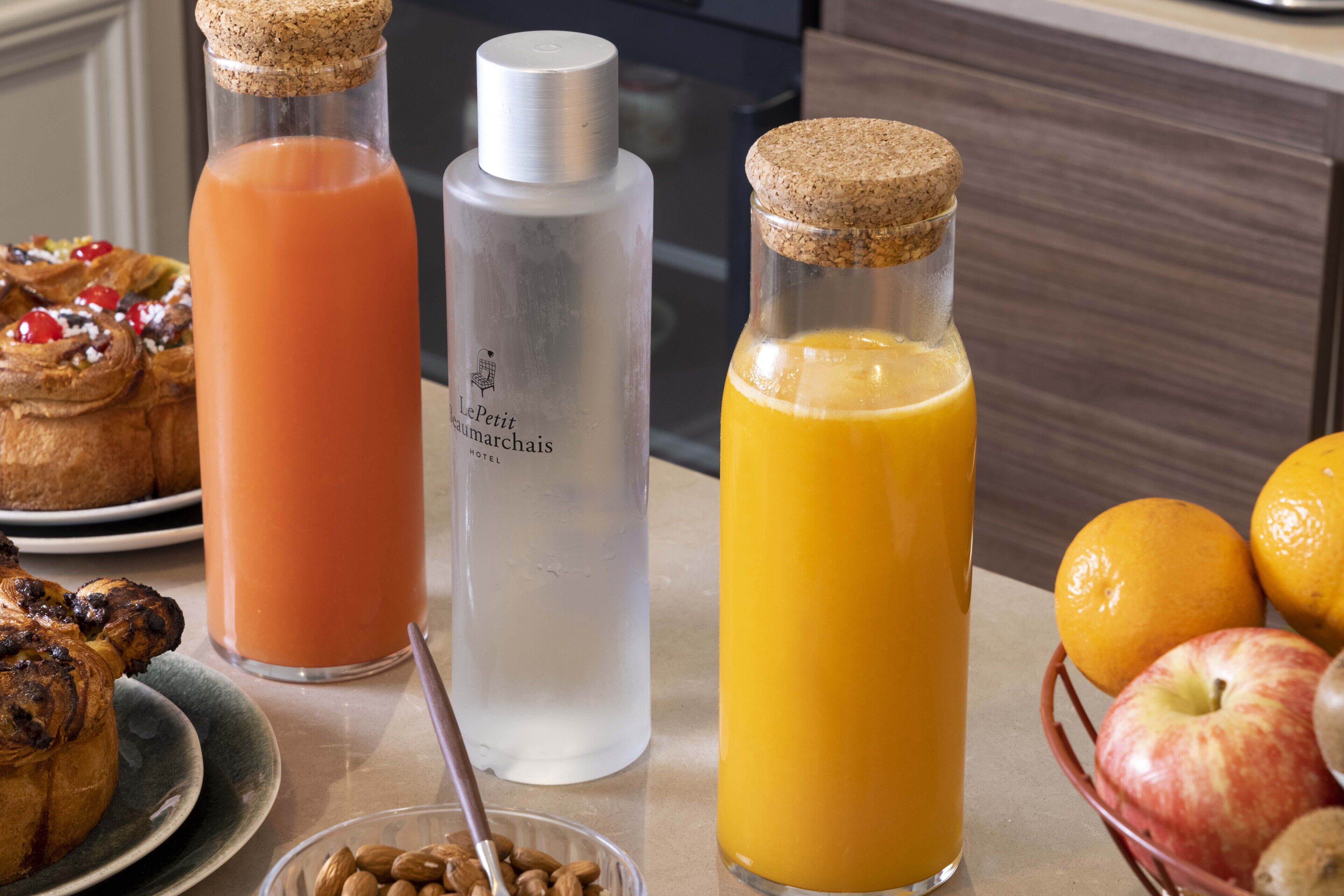 A breakfast setting with croissants, orange juice, and a bottle of water.