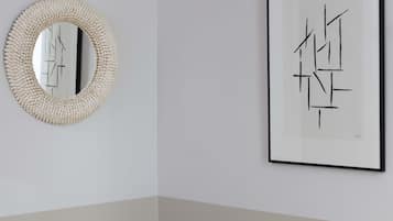 A framed abstract artwork and a textured mirror on a plain wall.