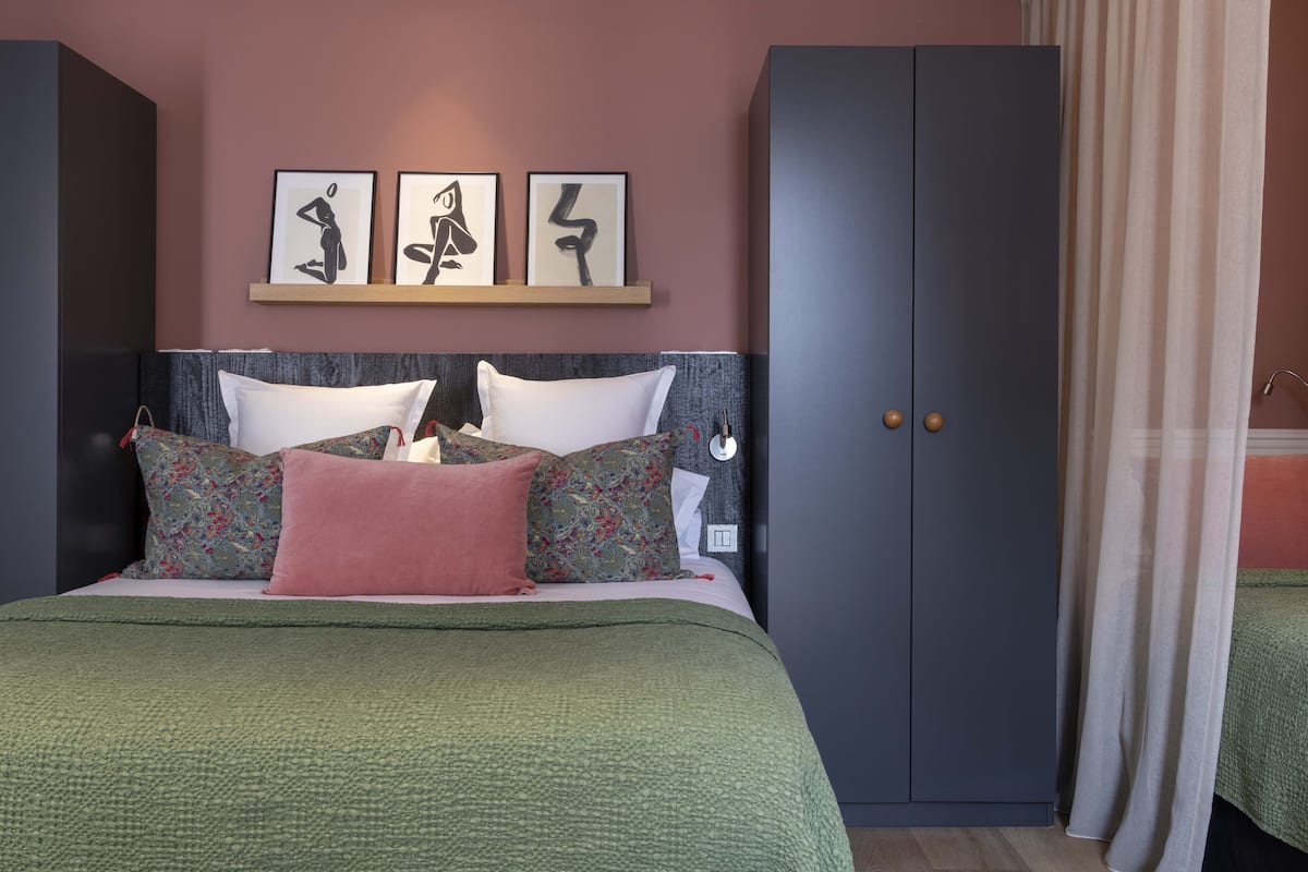 Ein Schlafzimmer mit Bett, Kissen, einem Kleiderschrank und Wandbildern.