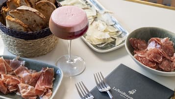 Una mesa servida con pan, una copa de vino tinto, y platos de jamón serrano y queso.