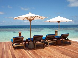 A wooden deck with lounge chairs and umbrellas overlooking a clear blue sea. - Helengeli Island Resort (Helengeli)
