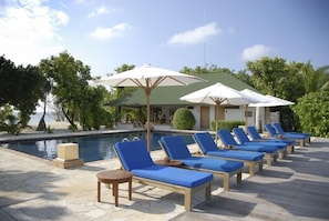 A poolside area with lounge chairs and umbrellas, a pool, and a building with a green roof. - Helengeli Island Resort (Helengeli)