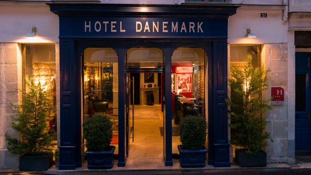 The entrance to Hotel Danemark with a dark facade, arched windows, and potted plants. - Hôtel Danemark (Paris)