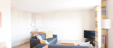 Una sala de estar moderna con un sofá, una mesa de centro y un televisor de pantalla plana.