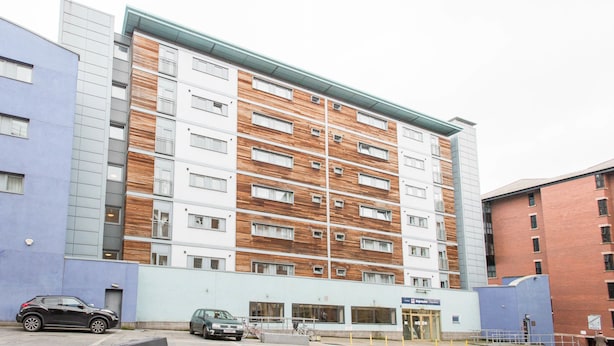 A multi-story hotel with a modern facade, featuring a mix of brick and wood paneling, and a prominent entrance with a blue awning. - PREMIER SUITES Newcastle (Newcastle-upon-Tyne)