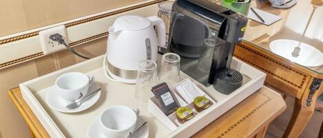 Un vassoio della colazione in camera d'albergo, con bollitore, macchina del caffè, tazze, piattini, un cucchiaino e salse.