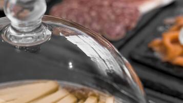Esposizione di cibi sotto una cupola di vetro, con pane a fette e un dolce rotondo su un piatto.