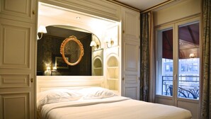 Une chambre d’hôtel avec un lit, un grand miroir et une fenêtre avec des rideaux.