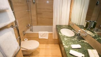 Un baño con inodoro, bañera y lavamanos con espejo.