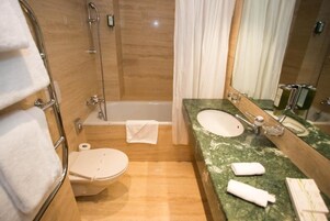 Un baño con inodoro, bañera y lavamanos con espejo.