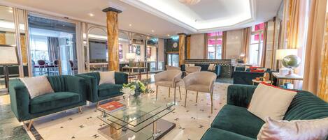 A spacious lobby with multiple seating areas, a glass coffee table, and a chandelier.