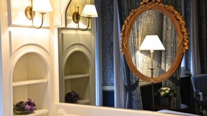 Une salle de bain avec un meuble-lavabo, un miroir doté d’un cadre décoratif et des appliques murales.