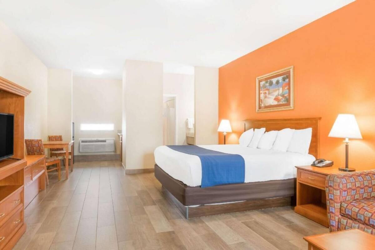 Een hotelkamer met een bed, nachtlampjes, een televisie, een bureau en een stoel.