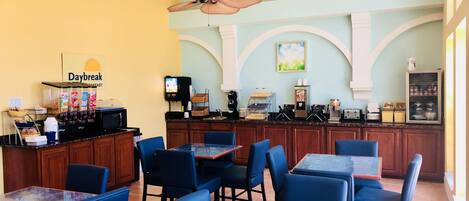 A restaurant with a breakfast bar, seating area, and kitchen.