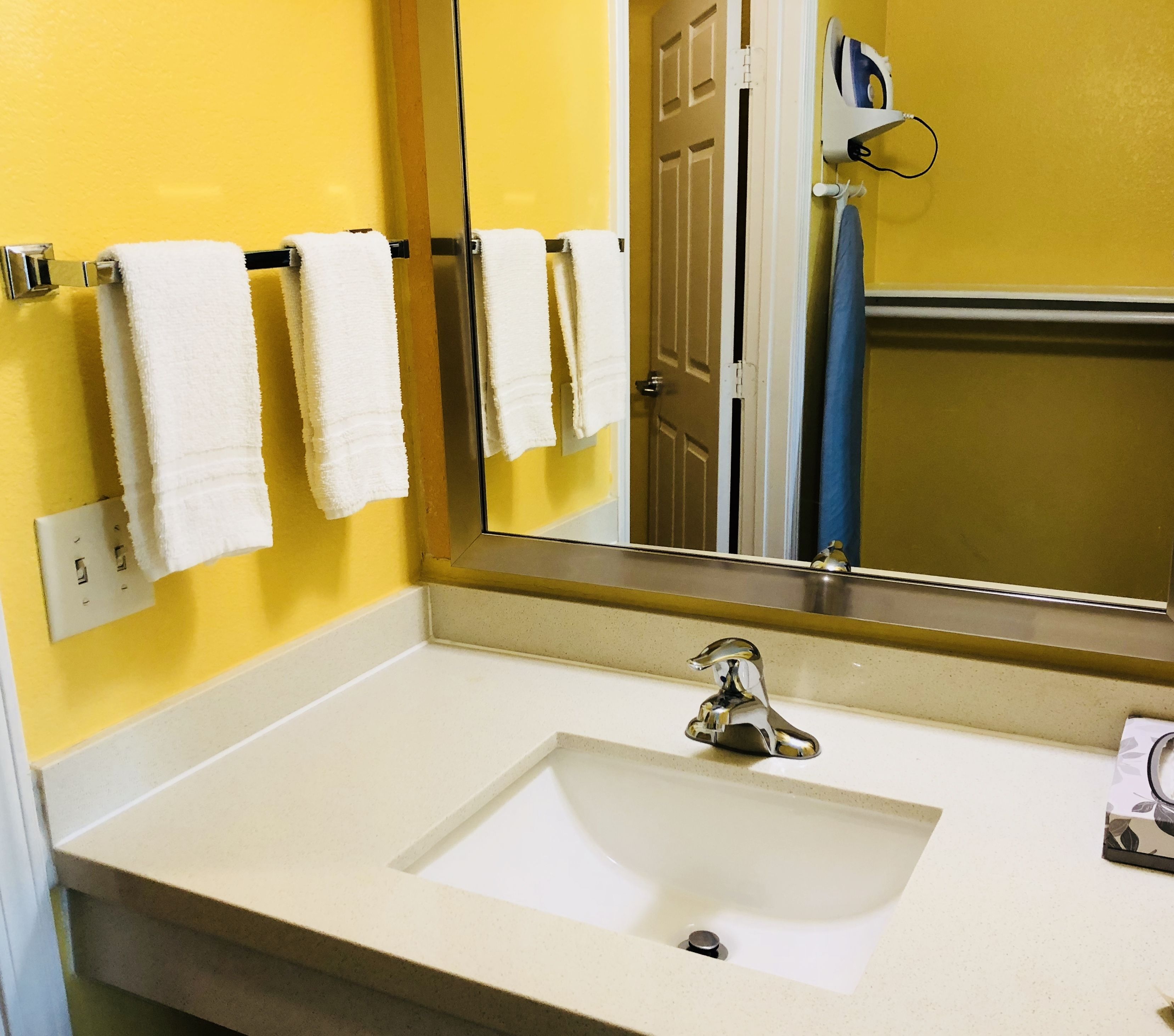 A bathroom with a white sink, a mirror, and a towel rack with white towels.