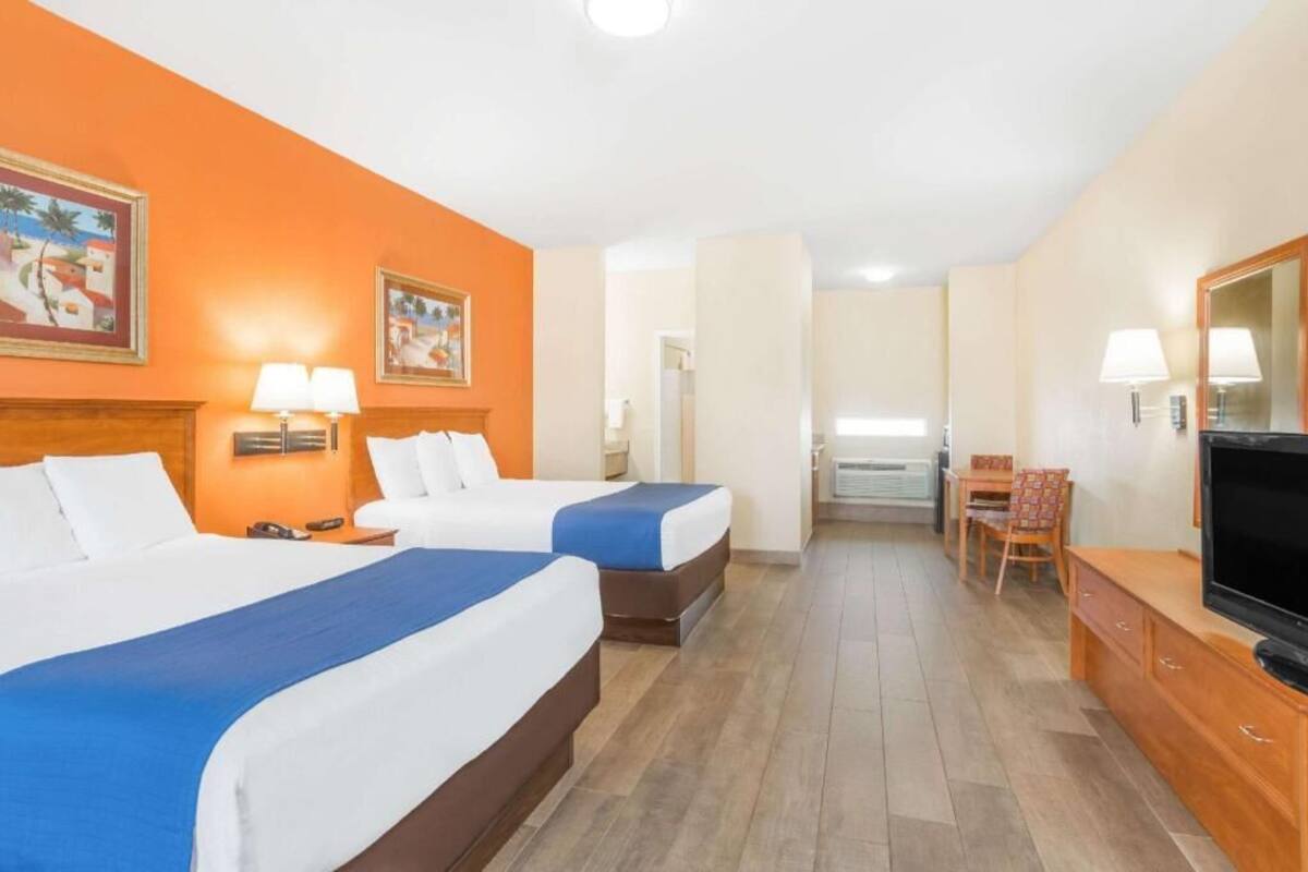 Een hotelkamer met twee bedden, een televisie, een bureau en een stoel.
