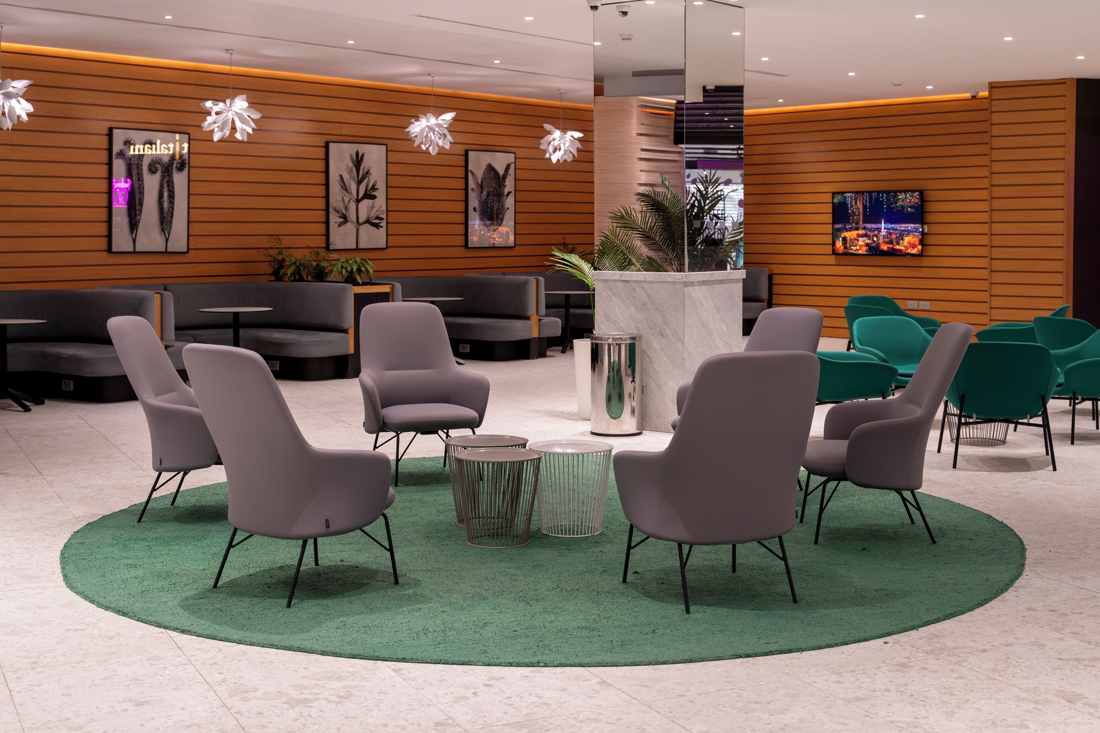 A modern lobby with grey and green seating, a central coffee table, and wall-mounted artwork.