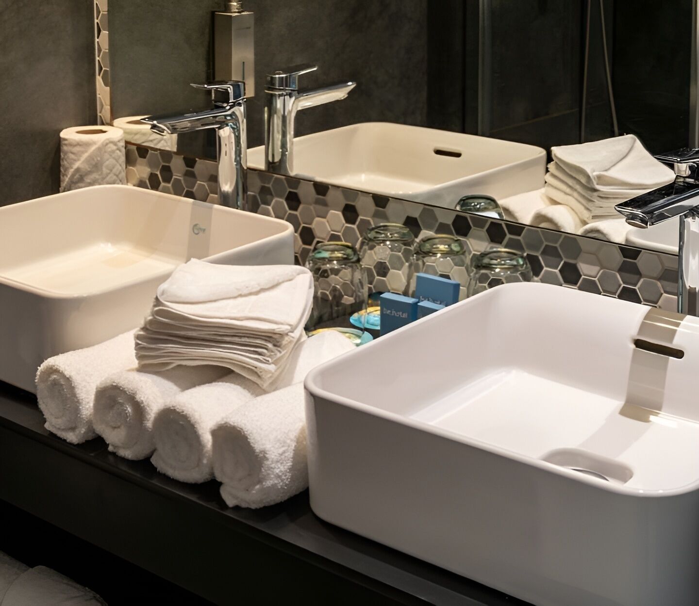 Une salle de bain avec deux lavabos, un miroir et un porte-serviettes où sont pliées des serviettes.