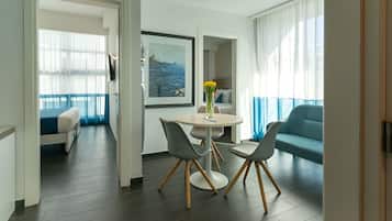 Une chambre d’hôtel moderne avec un balcon, un coin repas comprenant une table et des chaises, et un canapé.