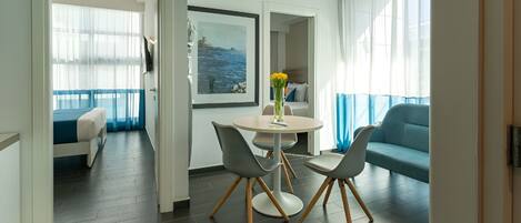 Une chambre d’hôtel moderne avec un balcon, un coin repas comprenant une table et des chaises, et un canapé.