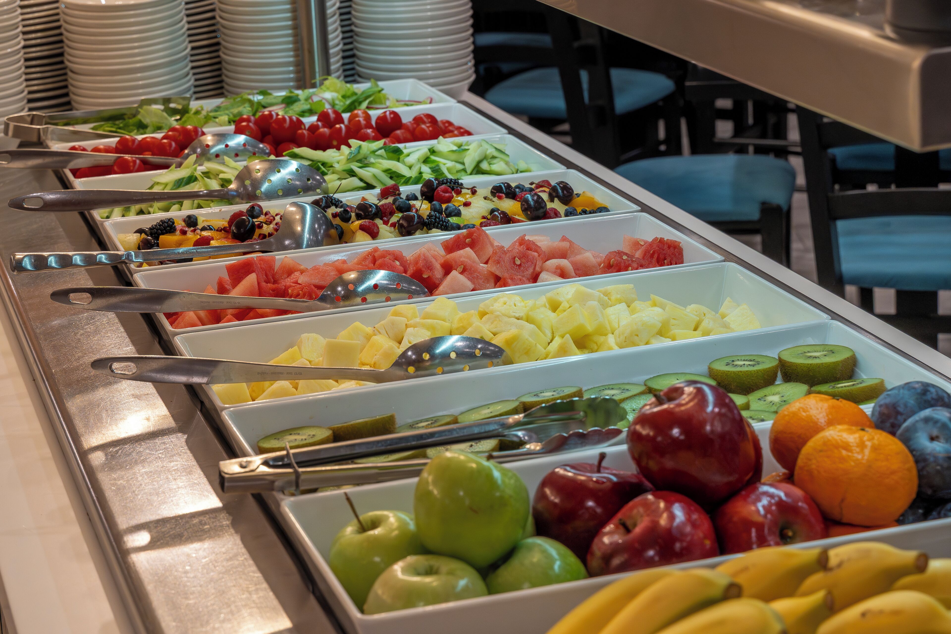 A buffet with various fruits and vegetables arranged in separate trays.