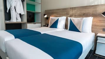A hotel room with two beds, a wardrobe, and a nightstand.
