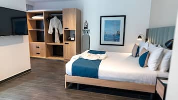 Una habitación de hotel moderna con una cama, un armario, un televisor y un cuadro en la pared.