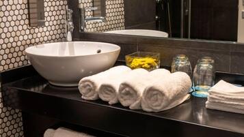 Un baño con un lavamanos de estilo pedestal, un espejo y toallas dobladas con cuidado en la encimera.