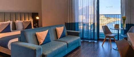 Una habitación de hotel moderna con un sofá azul, una mesita con sillas y un balcón con vistas.