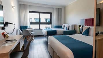 Una habitación de hotel con escritorio, dos camas, un ventanal grande y televisión.