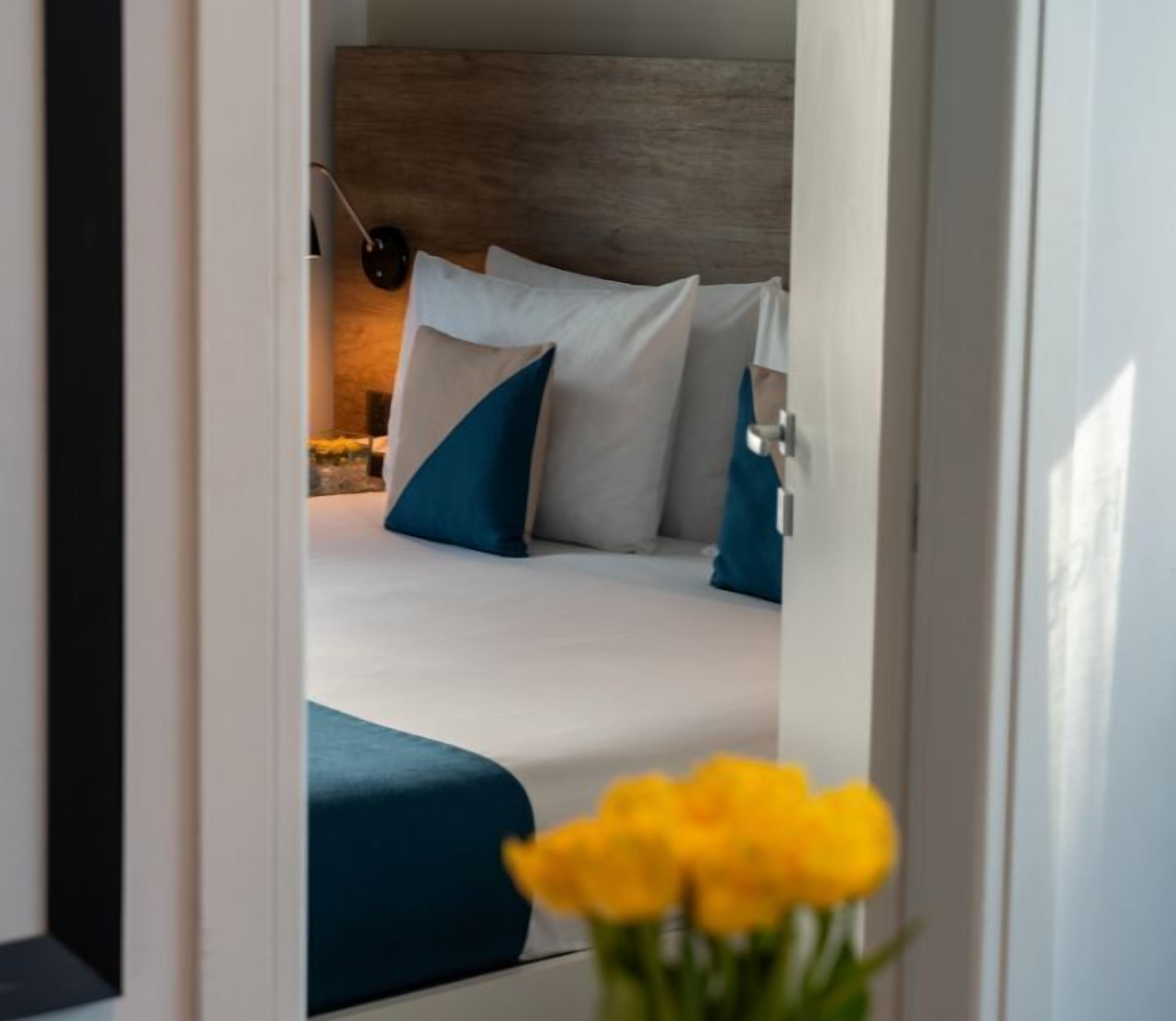 A bedroom with a bed, pillows, a nightstand, and a lamp.