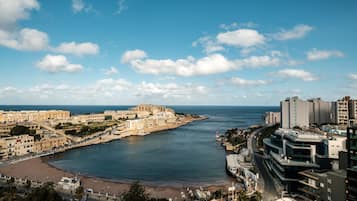 Un paisaje costero con playa, edificios históricos y rascacielos modernos.