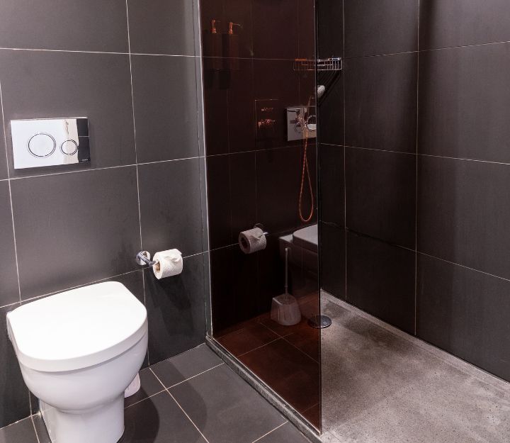 A bathroom with a toilet, a shower, and a glass-enclosed shower area.