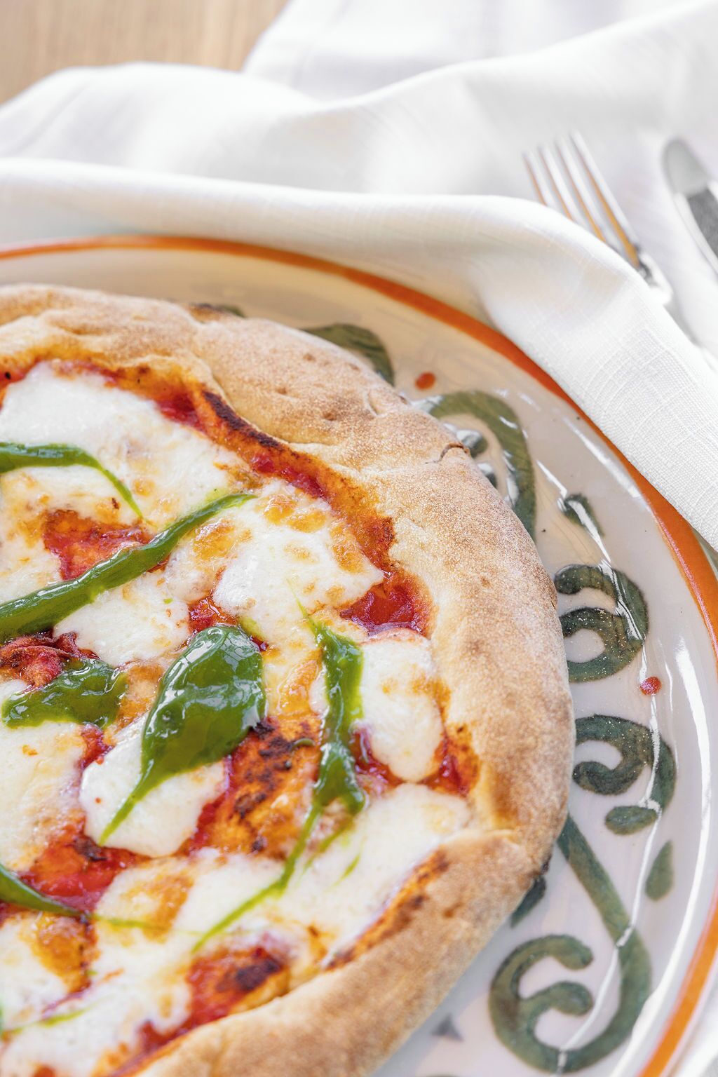 A pizza on a plate with a white and orange rim.