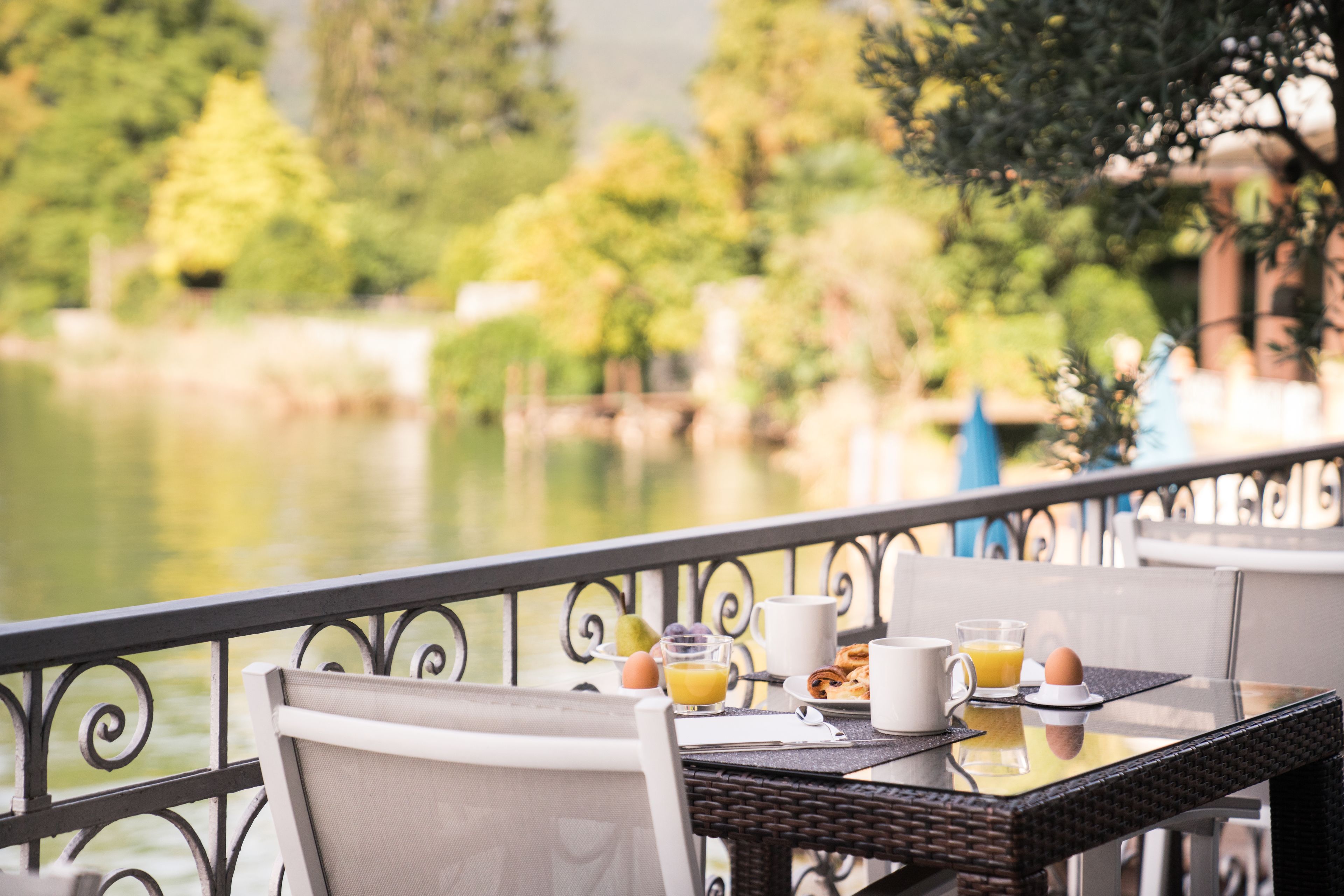 A dining table with breakfast items, a chair, and a view of a lake.