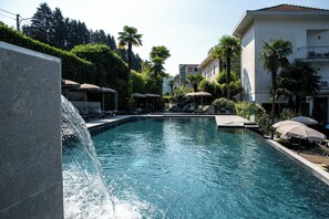 Una piscina al aire libre, sillones reclinables de piscina