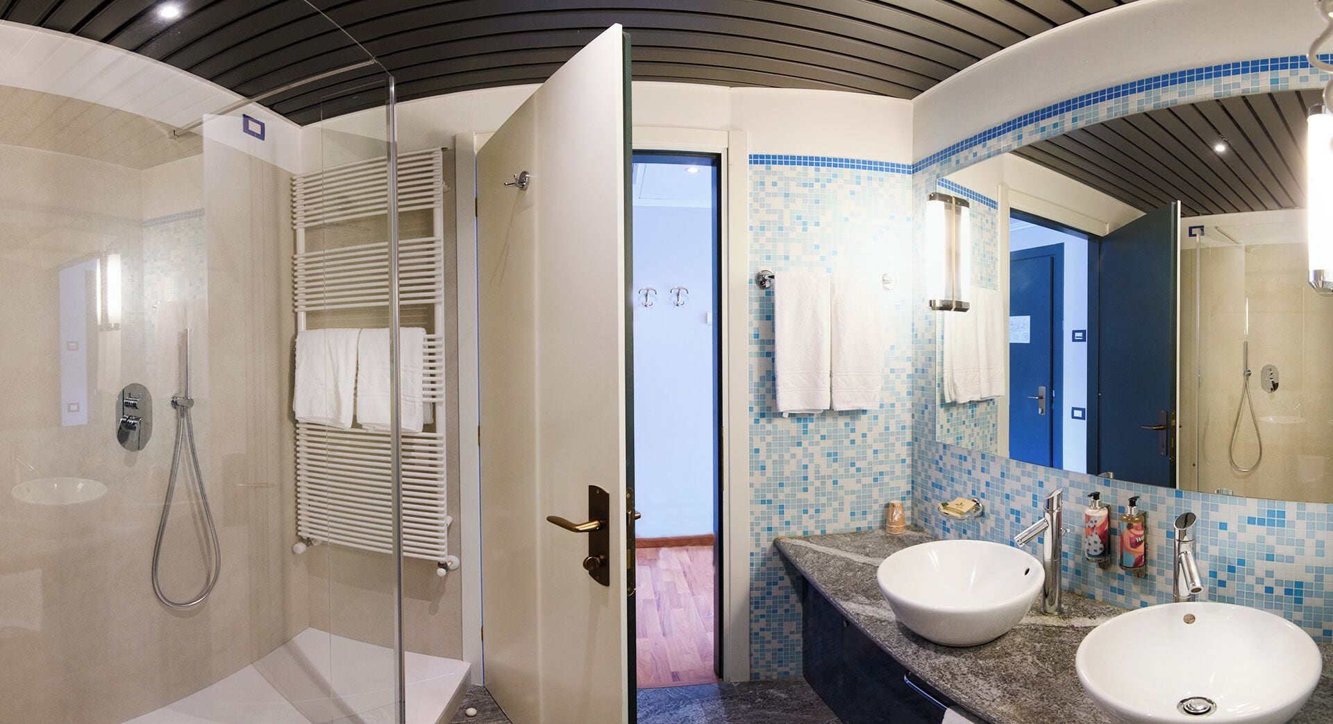 Une salle de bain moderne dotée d’une douche à parois de verre, de deux lavabos et d’un grand miroir.