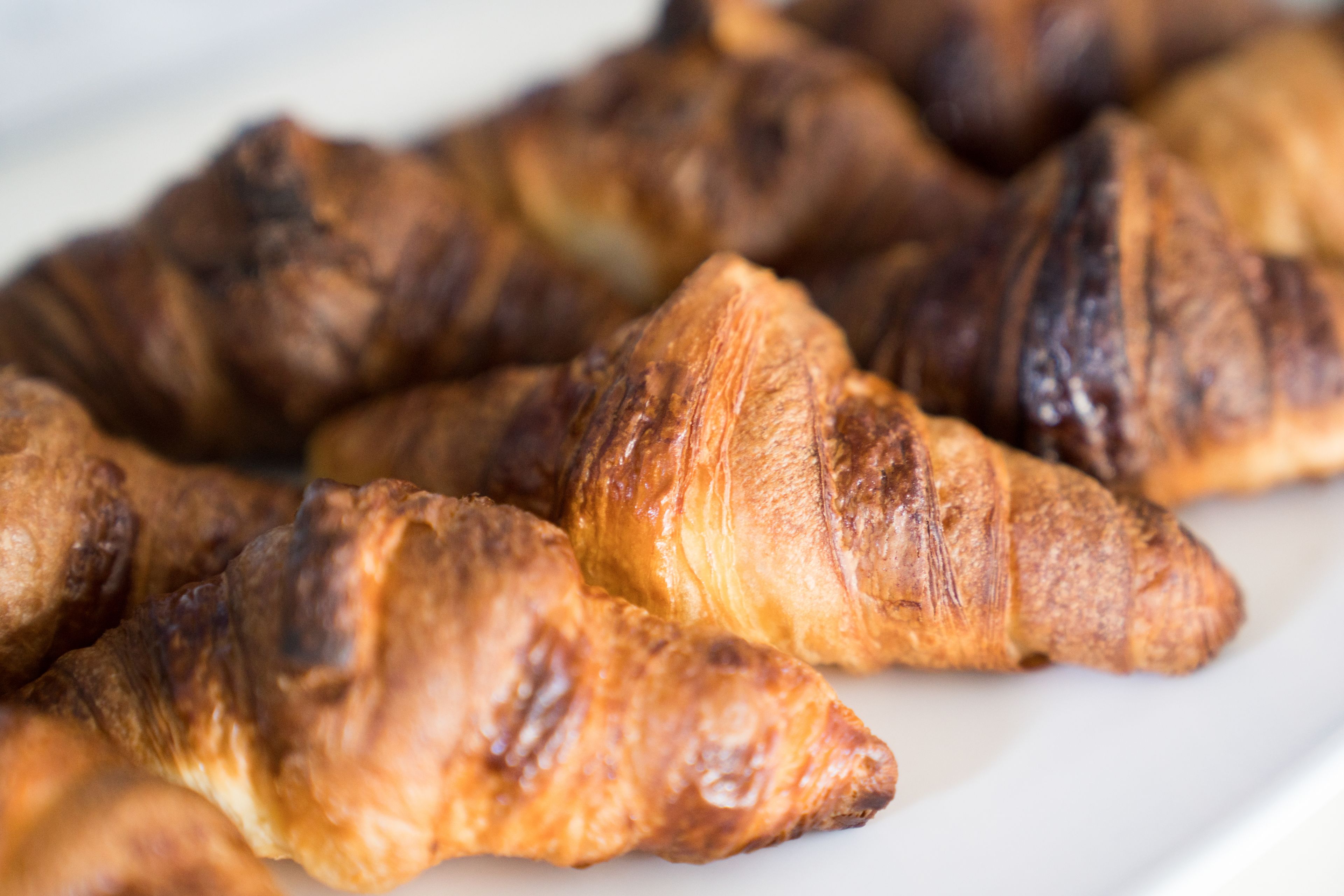 Een close-up van verschillende goudbruine croissants op een wit bord.