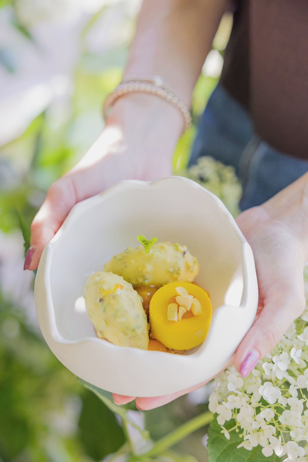 Una persona sostiene un tazón blanco con tres dumplings y una porción de fruta amarilla.