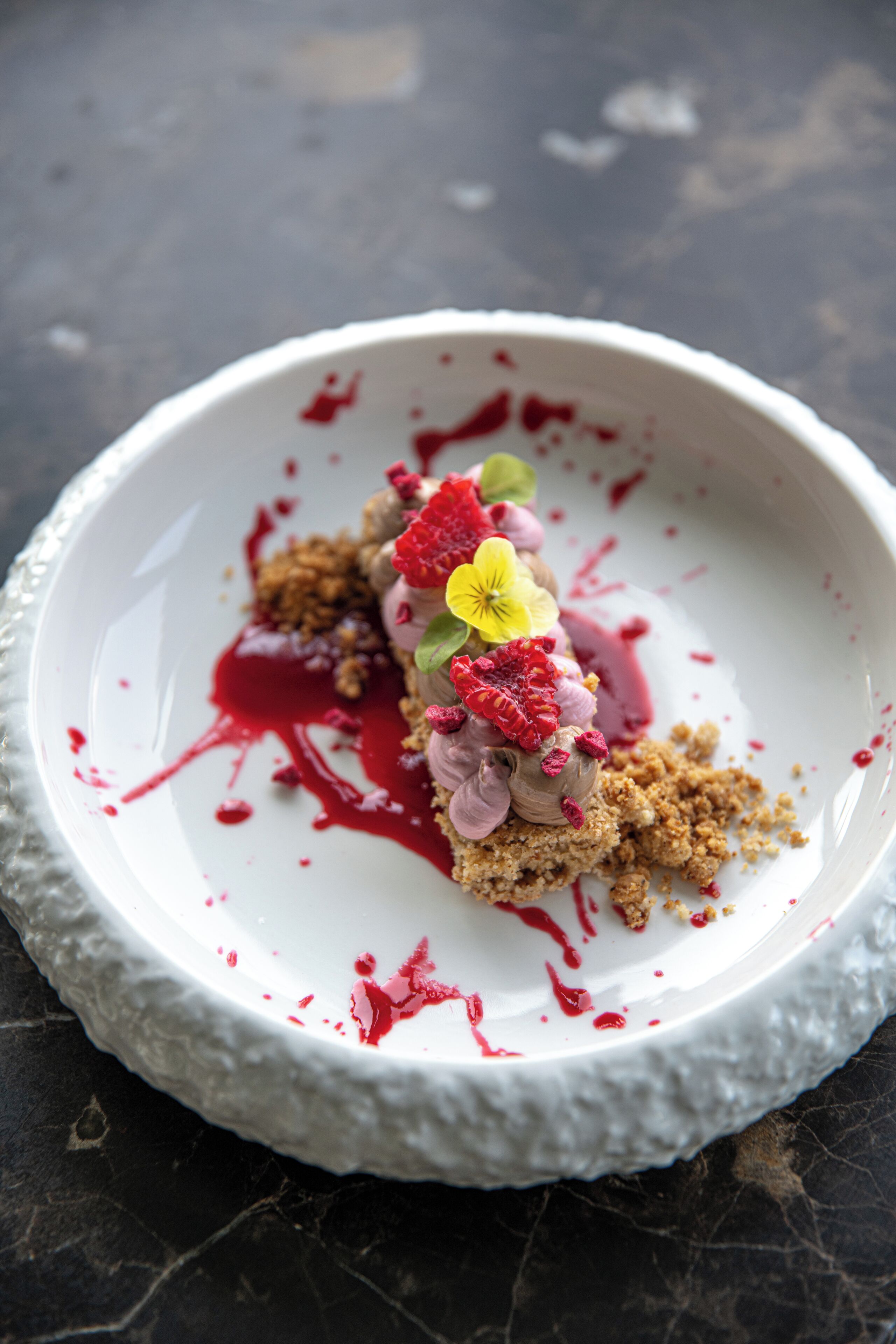 A dessert on a white plate with a textured edge, placed on a dark surface.