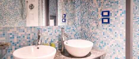 Un baño con dos lavamanos, ducha y pared con azulejos.