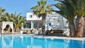 Een buitenzwembad, parasols bij het zwembad en ligstoelen