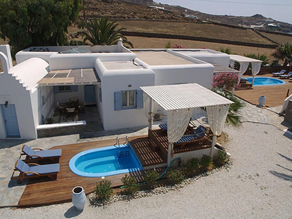 A modern villa with a pool, outdoor seating, and a covered patio.