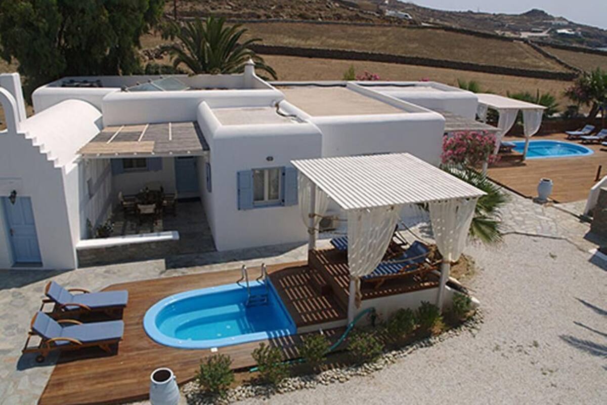 A modern villa with a pool, outdoor seating, and a covered patio.