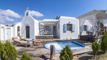 A white villa with a pool, outdoor seating, and a pergola.