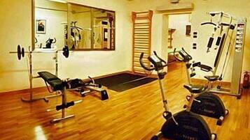 A gym with exercise equipment, a mirror, and a wooden floor.