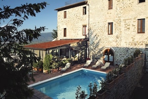 Un edificio de piedra con piscina, zona de estar al aire libre y vistas al paisaje.