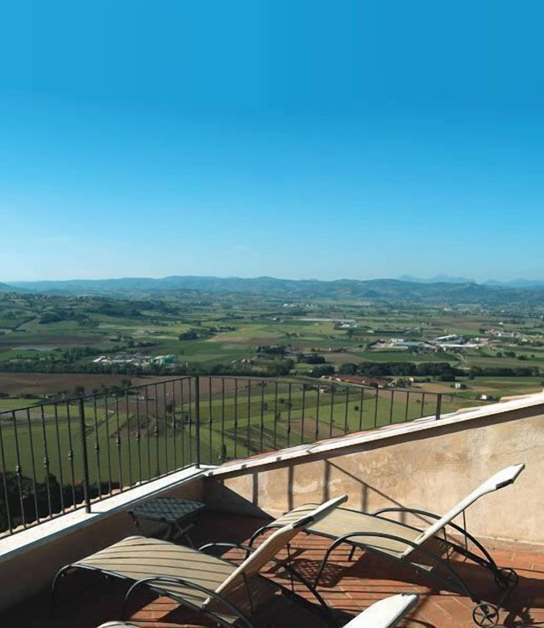 A balcony with a view of rolling hills and a clear blue sky.
