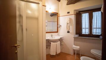 Un baño con lavabo, espejo, inodoro y ventana con cortinas.