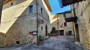 Un vicolo stretto con edifici in pietra, un cartello per un ristorante e una bandiera.